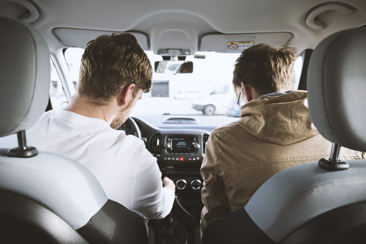 Fahrschüler und Fahrlehrer von hinten im Auto während einer Fahrstunde